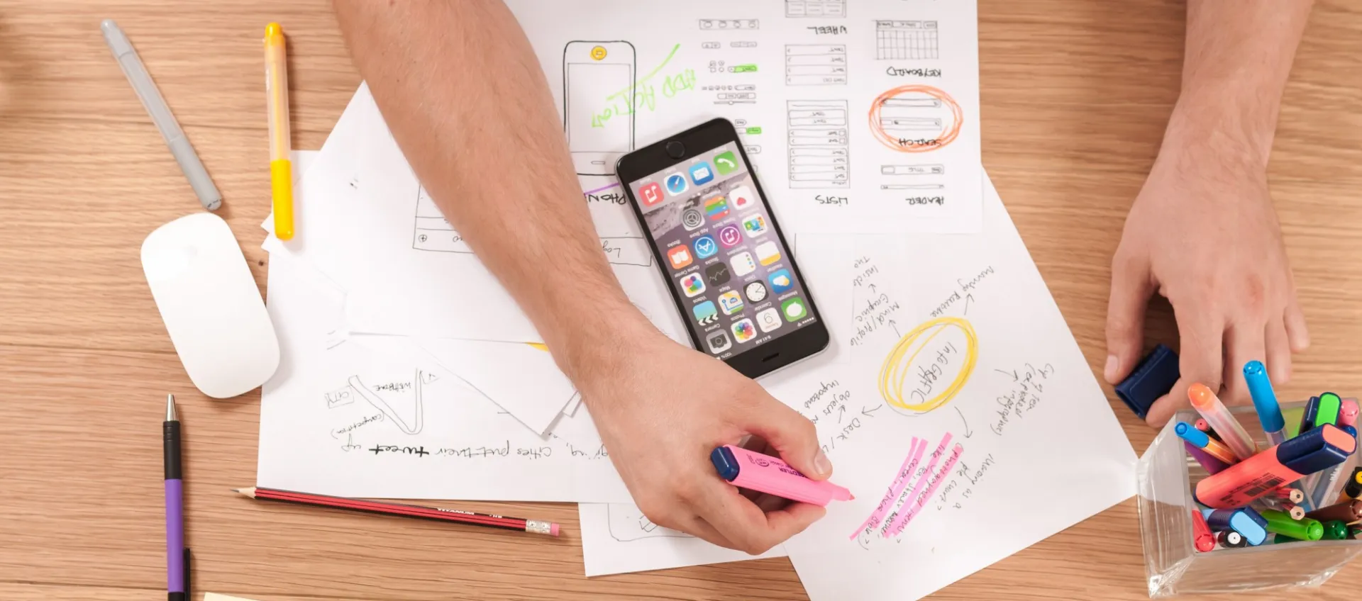 Overhead shot of student making notes on paper in front of a monitor.